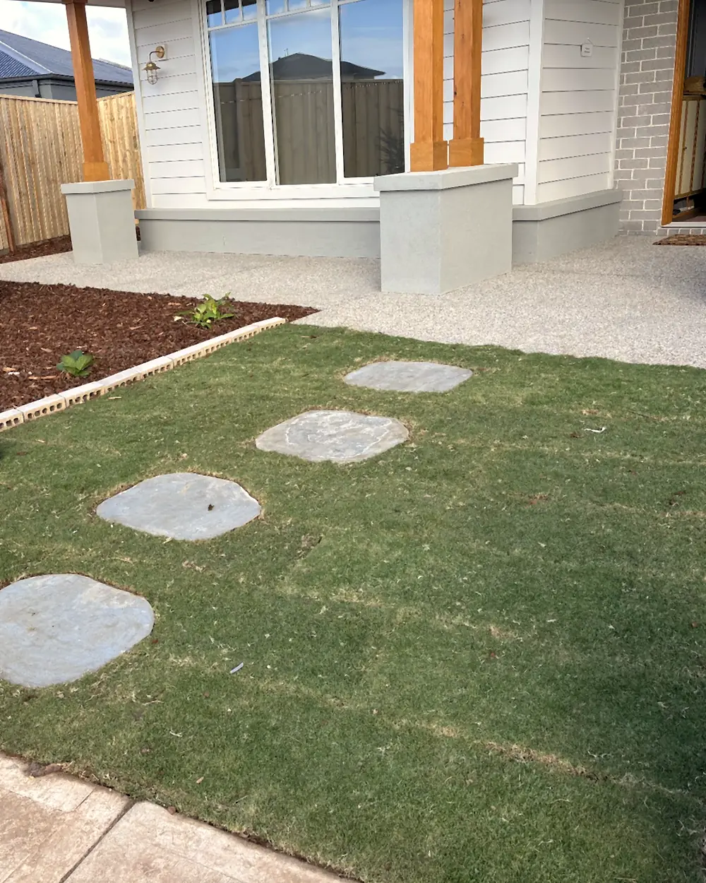 Front lawn with round stepping stones and a fresh mulched garden bed, finished by Rick's Landscaping