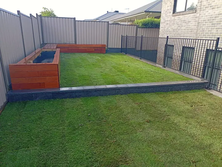 Raised timber planter boxes beside fresh lawn and a charcoal block retaining edge