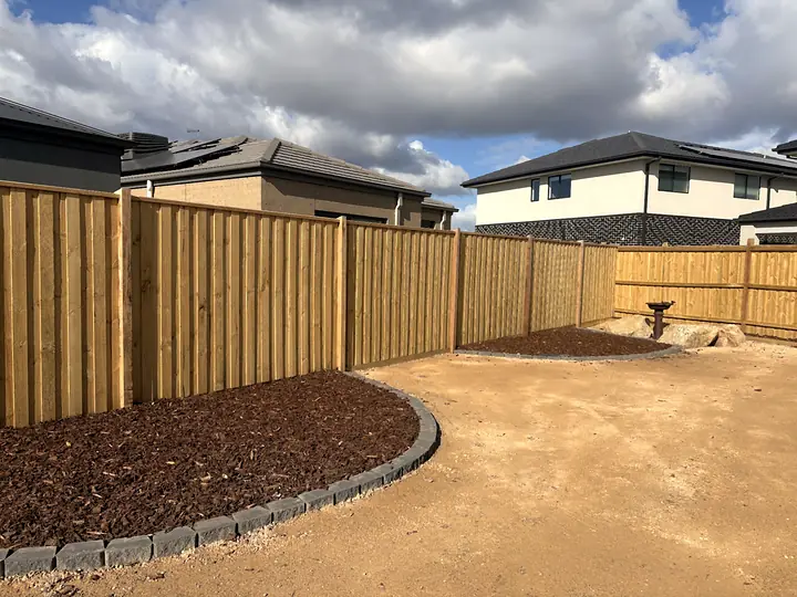 New timber paling fence with a mulched garden bed and curved block edging