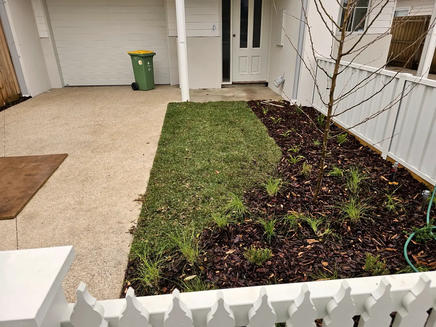Front garden with new turf, fresh planting and mulch beside an exposed aggregate driveway